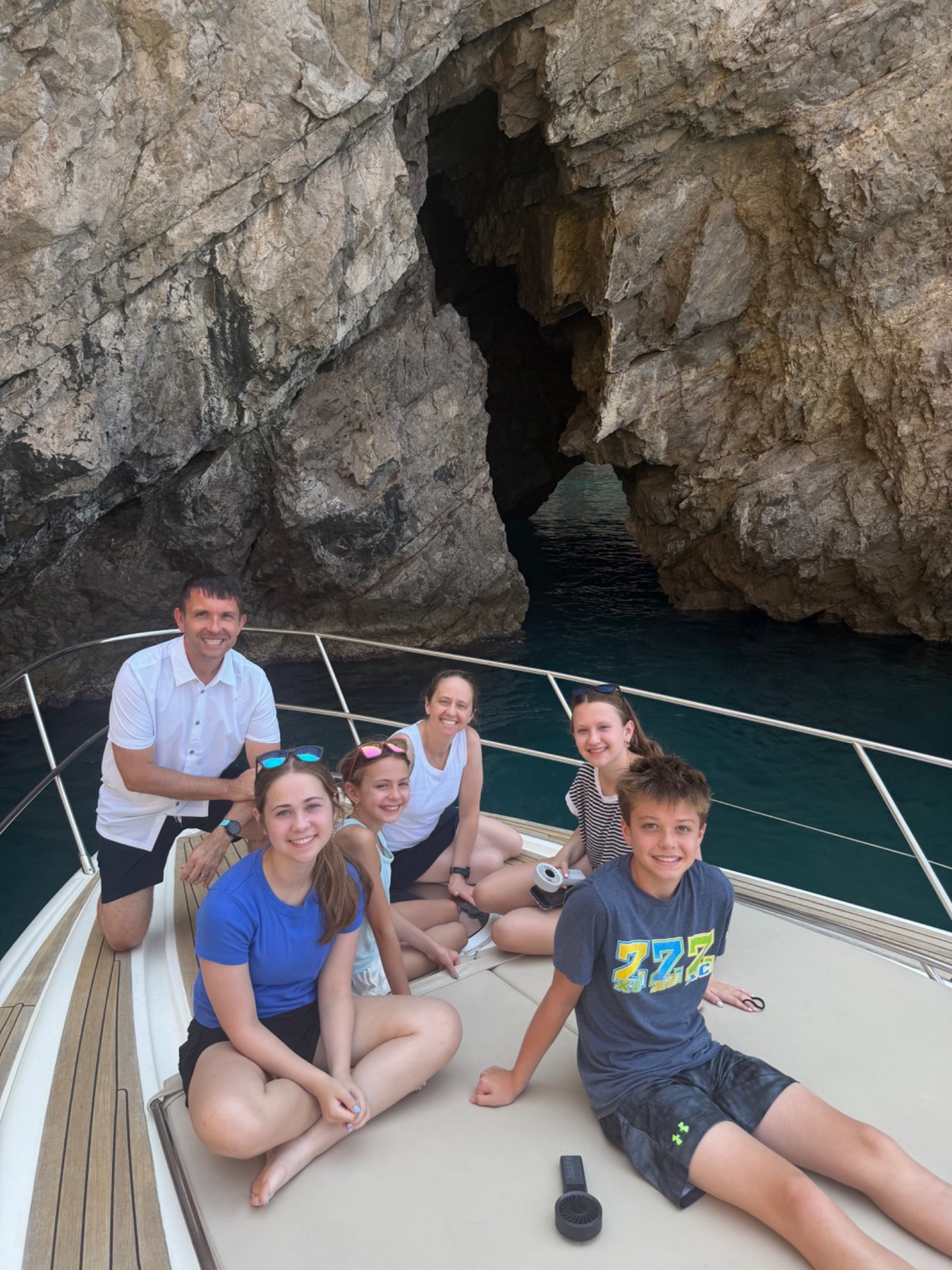 Kim's family smiling together aboard their private boat in Italy